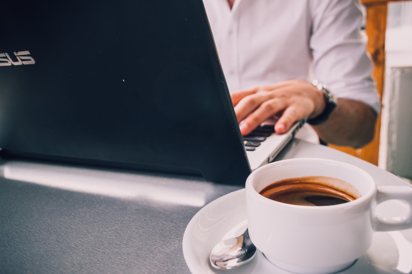 Um homem fazendo a consulta nfe completa em seu computador enquanto toma uma xícara de café.